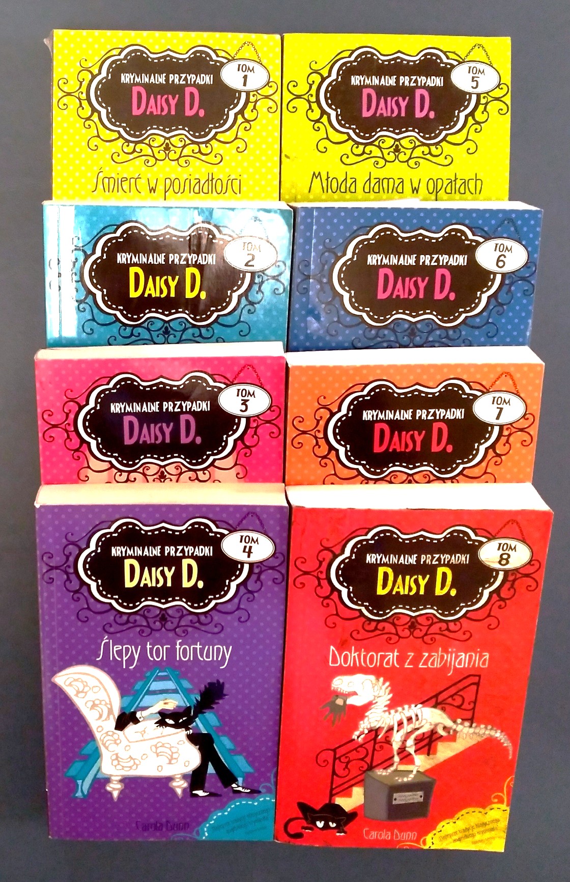 Polish-language set of eight (8) volumes, complete of the Daisy Dalrymple series, complete: Tom 1: Smiert w posiadtosci Wentwaterow; Tom 2: Tajemnica ogrodu zimowego; Tom 3: Oklaaski zbierze morderca; Tom 4: Slepy tor fortuny; Tom 5: Mloda dama w opatach; Tom 6: Wet za wet, milordzie; Tom 7: Zaczeto